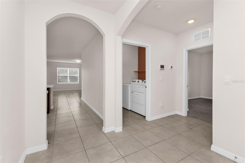A tiled hallway leads to an arched opening, a laundry room, and a carpeted bedroom — 26567 DEEP CREEK BOULEVARD, PUNTA GORDA, FL