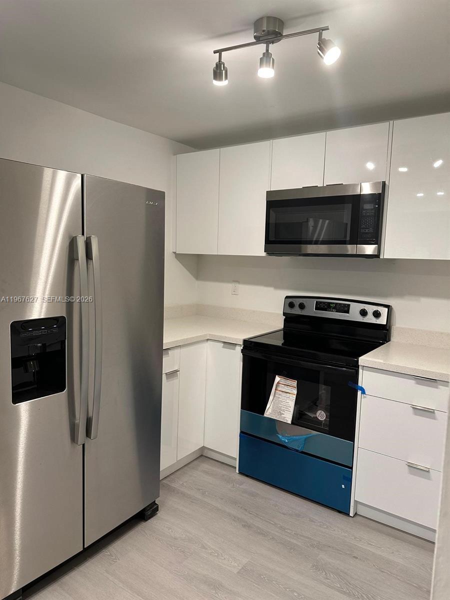 A modern kitchen features stainless steel appliances, white cabinetry, and light-colored countertops — 210 SW 11th St # 510, Miami FL 33130, MIAMI, FL