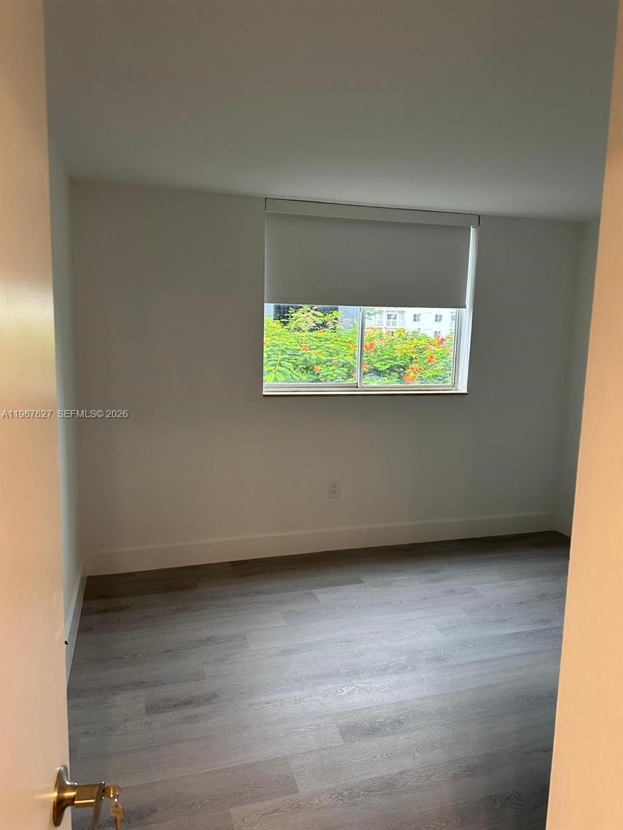 An empty bedroom features light gray wood-look flooring, white walls, and a window with blinds — 210 SW 11th St # 510, Miami FL 33130, MIAMI, FL