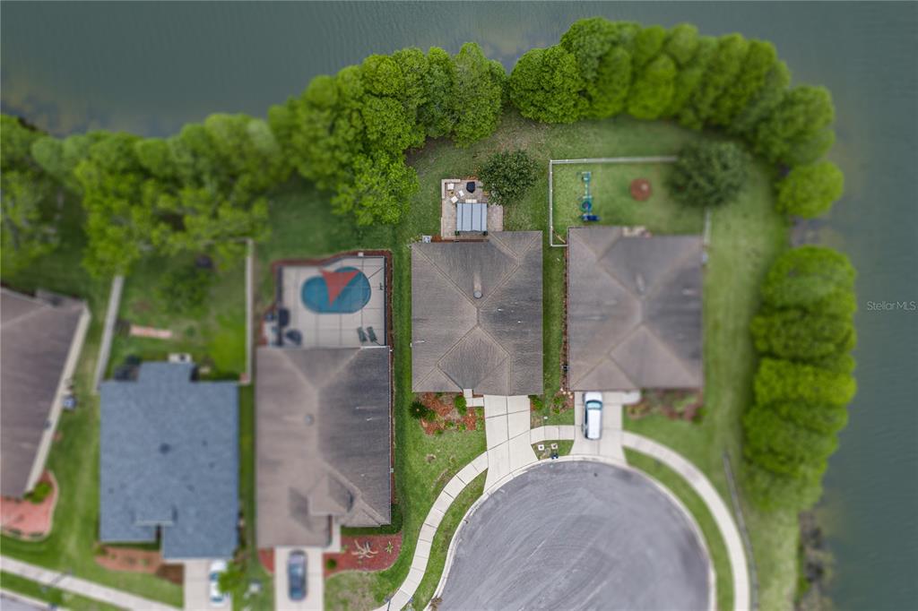 An aerial view shows three suburban houses with pools and backyards bordering a lake — 5544 HURON WAY, LAKELAND, FL