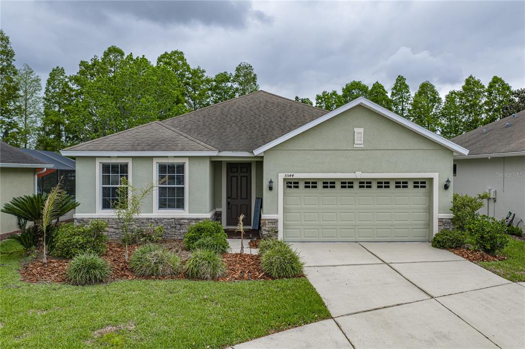 A single-story house with a light green exterior, stone accents, and a two-car garage — 5544 HURON WAY, LAKELAND, FL
