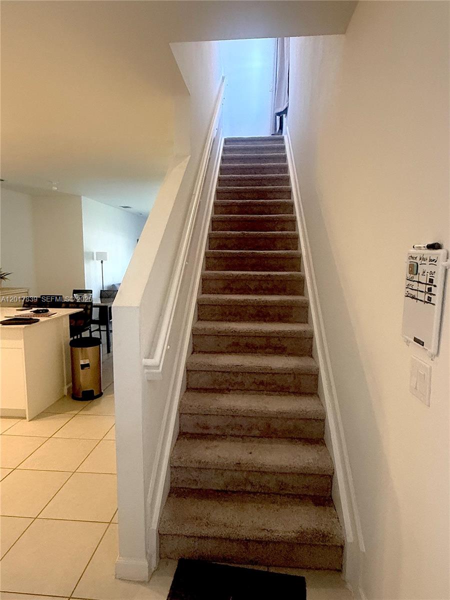 A carpeted staircase leads to an upper level in a home with tiled flooring — 4941 Oakmont Dr # 5838, Dania Beach FL 33312, DANIA BEACH, FL