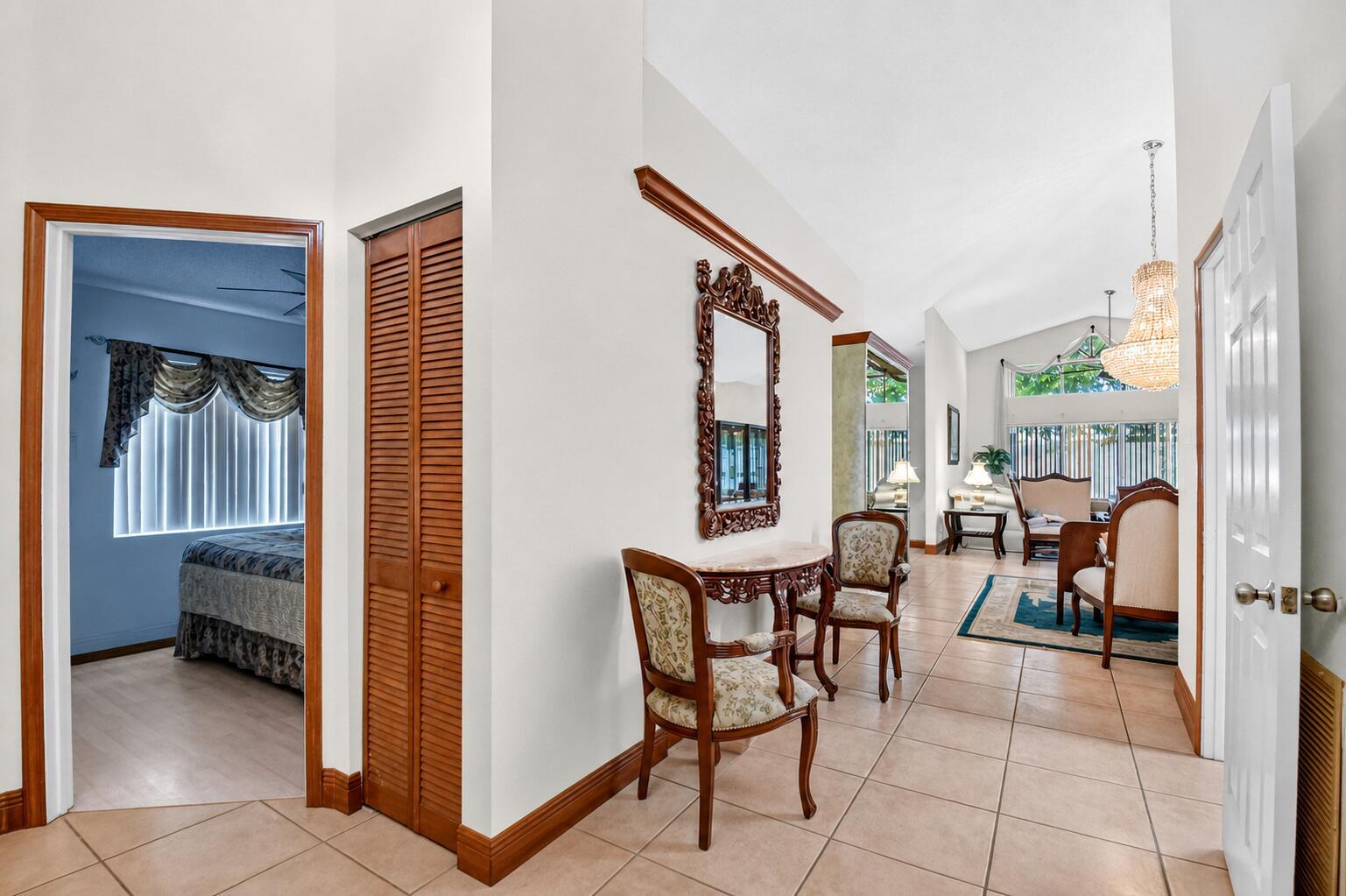 A tiled hallway features a small table with two chairs, a mirror, and a bedroom doorway — 1059 Fairfax Circle W, Boynton Beach FL 33436, BOYNTON BEACH, FL