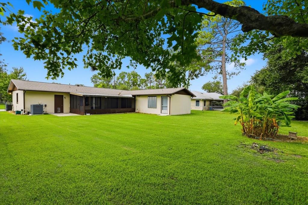The exterior of a single-story house features a screened-in porch and a large grassy yard — 10 FENWICK LANE, PALM COAST, FL