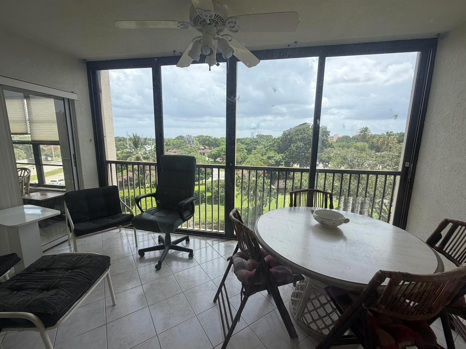 A sunroom with tile flooring, a dining set, and large windows overlooking a green landscape — 14475 Strathmore Lane # 501, Delray Beach FL 33446, DELRAY BEACH, FL