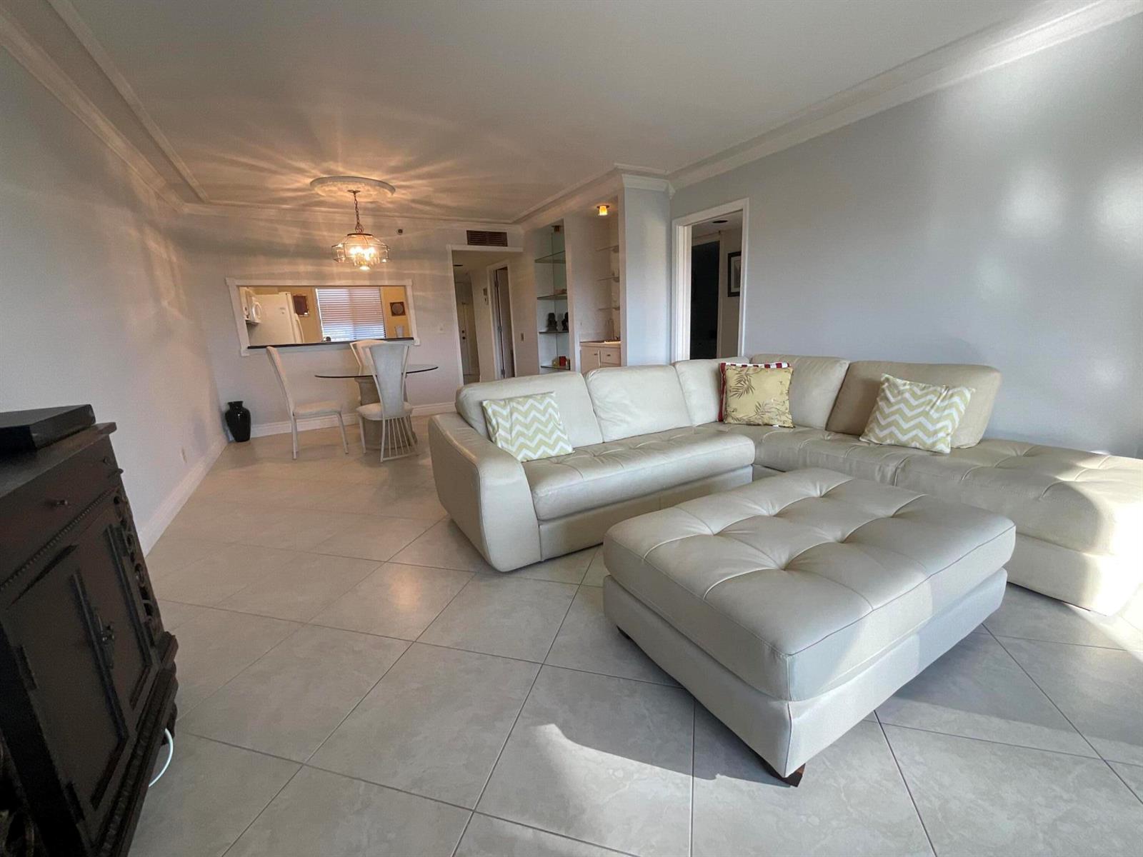 A living room features a white sectional sofa, matching ottoman, and a dining area — 14475 Strathmore Lane # 501, Delray Beach FL 33446, DELRAY BEACH, FL