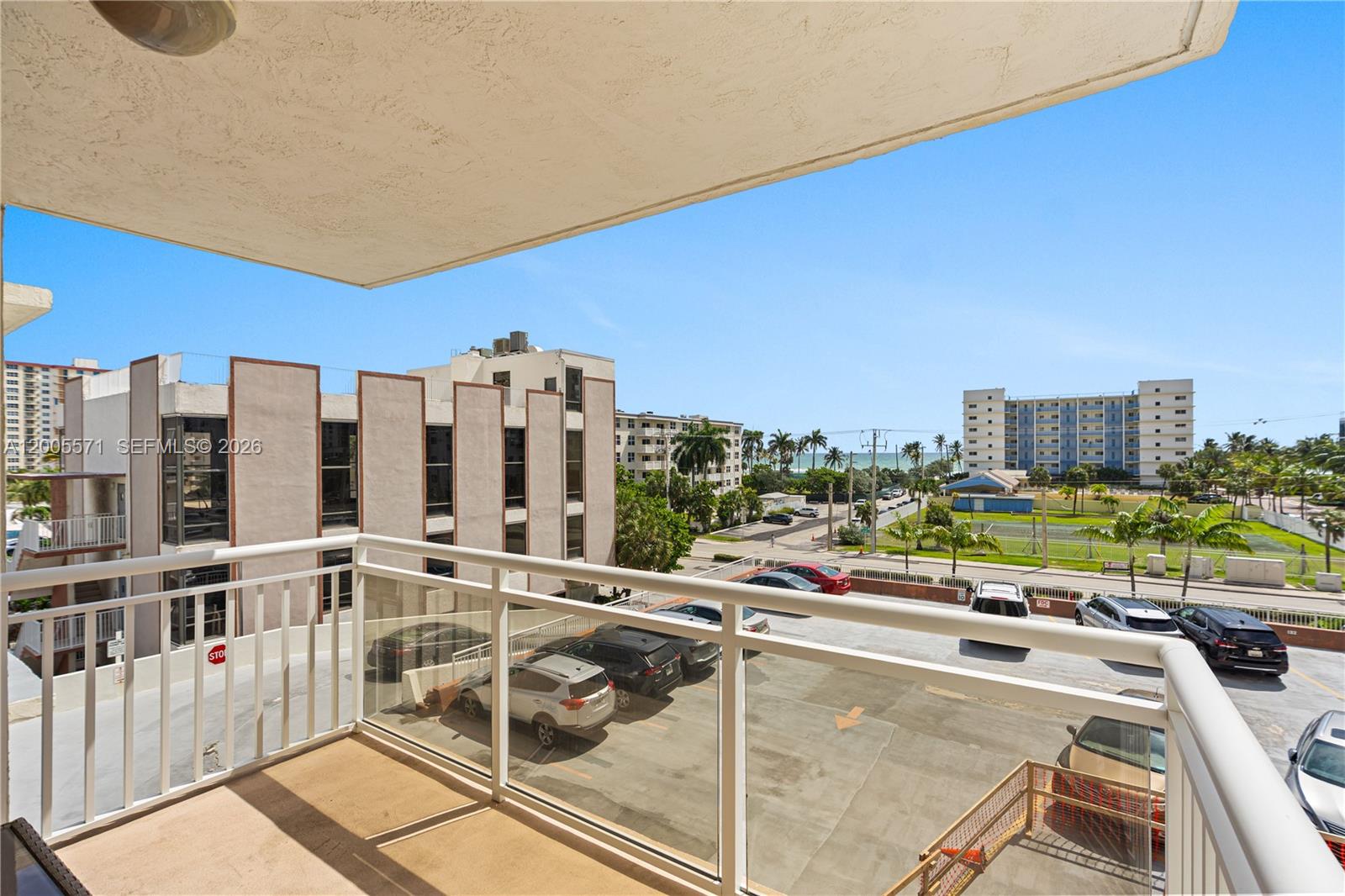 A balcony overlooks a parking lot, nearby buildings, and a distant view of the ocean — 1600 S Ocean Dr # 4G, Hollywood FL 33019, HOLLYWOOD, FL