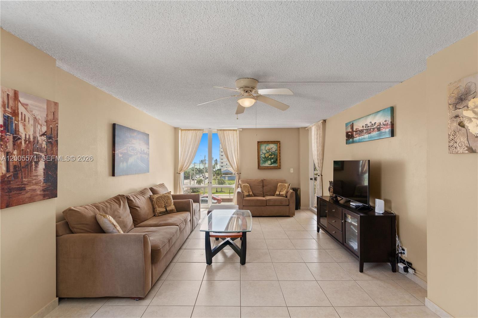A living room features beige tile floors, two brown sofas, a glass coffee table, and a television — 1600 S Ocean Dr # 4G, Hollywood FL 33019, HOLLYWOOD, FL