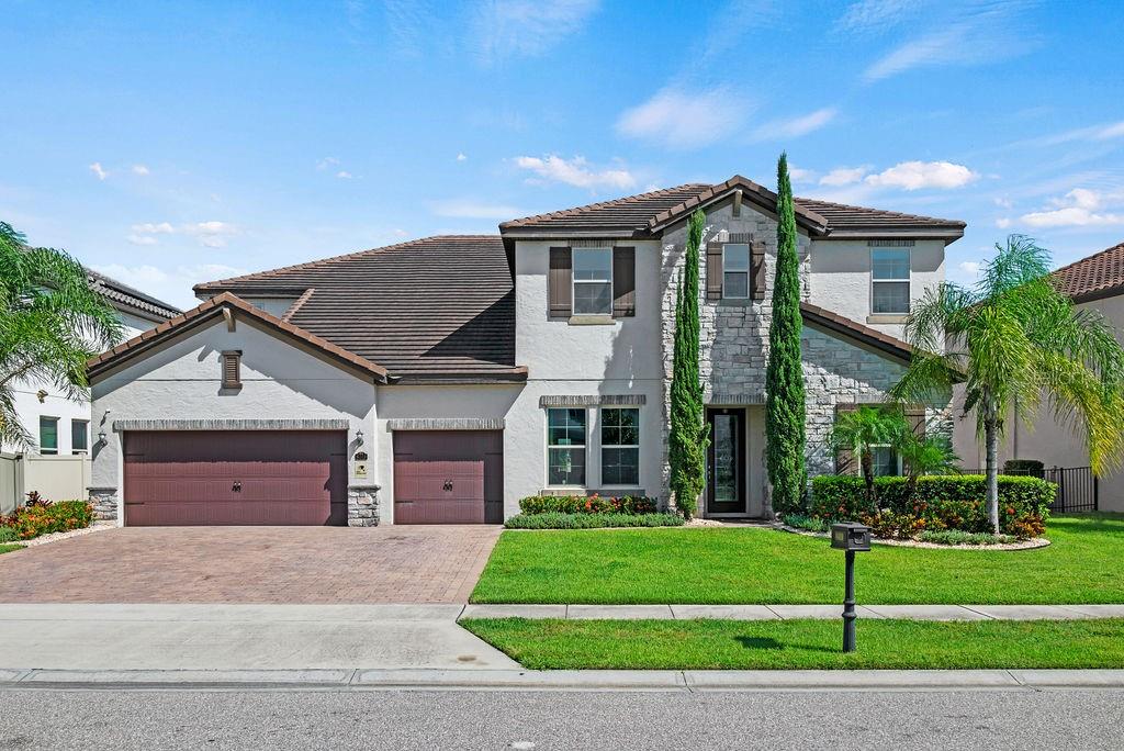 A two-story suburban house with a three-car garage, stone facade, and a manicured front lawn — 8419 KARWICK STREET, ORLANDO, FL