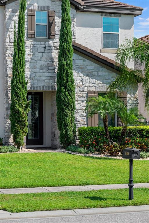 A two-story house features a stone facade, tall cypress trees, and a front yard mailbox — 8419 KARWICK STREET, ORLANDO, FL