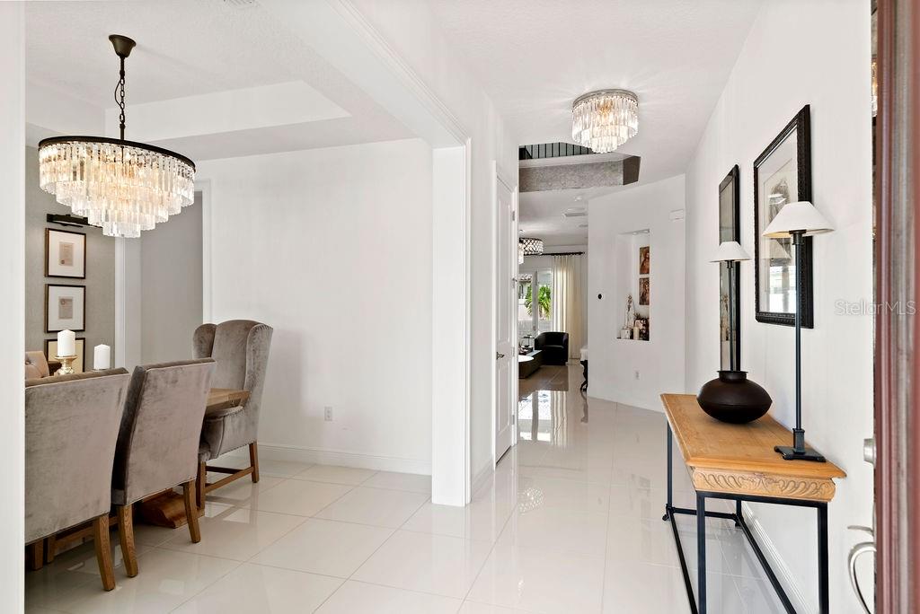 A bright entryway features white tile floors, a crystal chandelier, and a wooden console table — 8419 KARWICK STREET, ORLANDO, FL