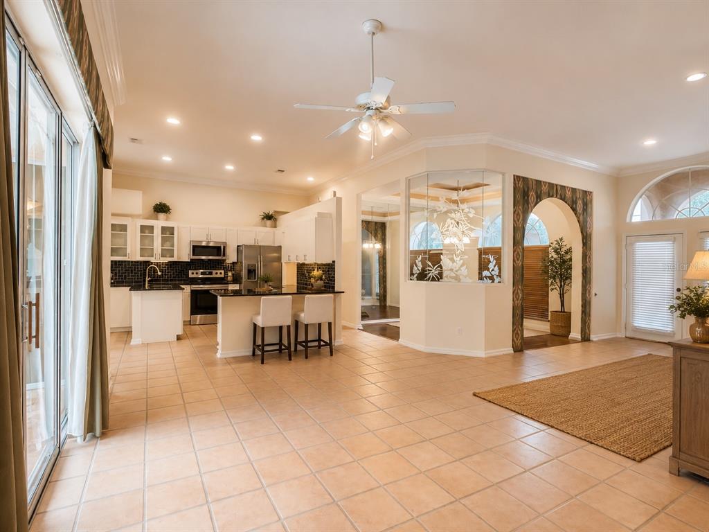 An open-concept kitchen and living area with tile floors, white cabinets, and an arched entryway — 6468 NW FRIENDLY CIRCLE, PORT ST LUCIE, FL