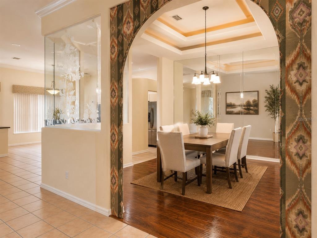 A dining room with a wooden table and chairs sits beneath a tray ceiling — 6468 NW FRIENDLY CIRCLE, PORT ST LUCIE, FL
