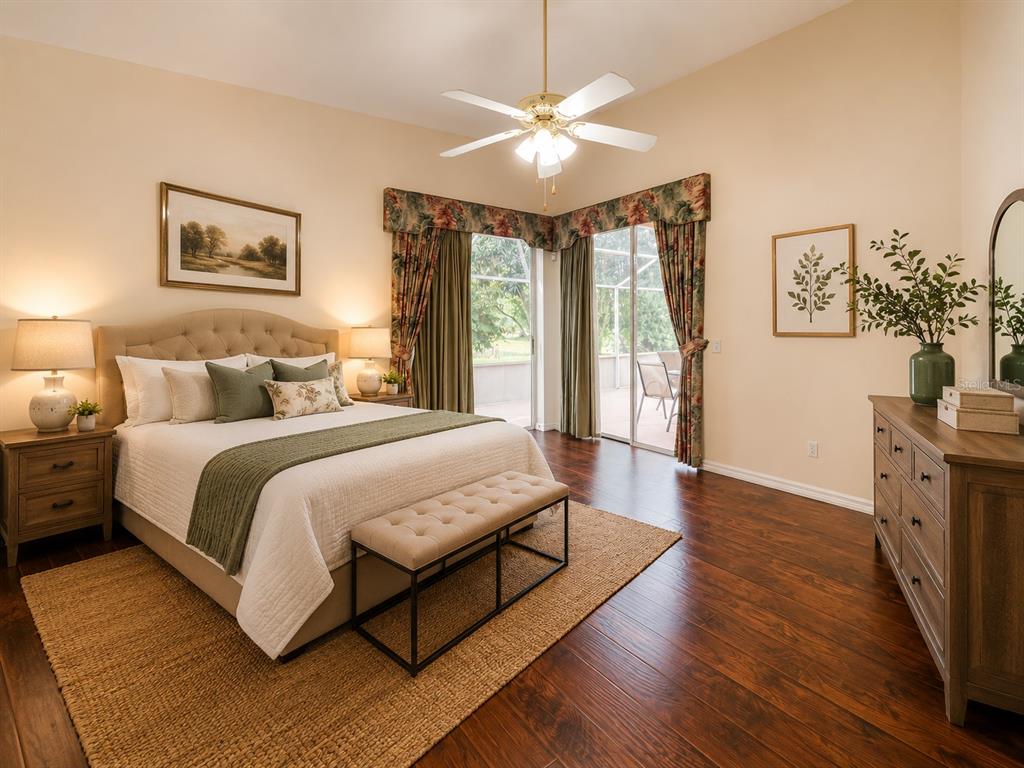 A bedroom features a tufted headboard, dark wood floors, and sliding glass doors to a patio — 6468 NW FRIENDLY CIRCLE, PORT ST LUCIE, FL
