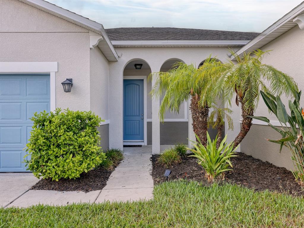 The exterior of a house features a blue front door, a garage, and a palm tree — 6307 4TH STREET E, BRADENTON, FL