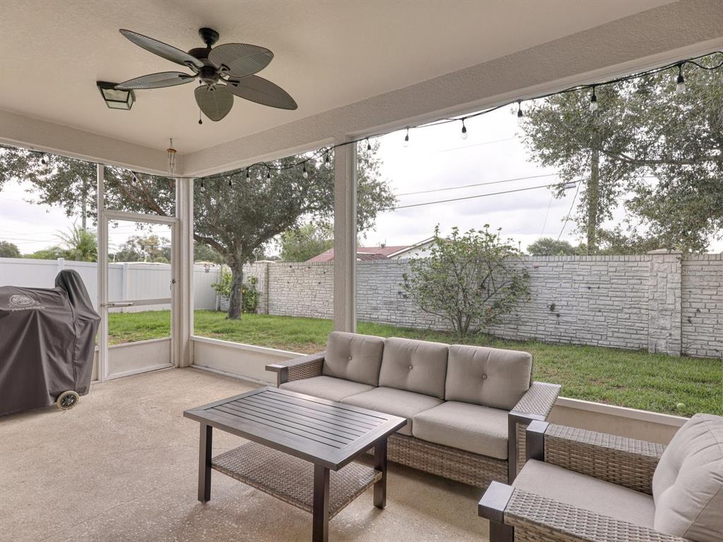 A screened-in patio features a ceiling fan, outdoor furniture, and a view of the backyard — 6307 4TH STREET E, BRADENTON, FL
