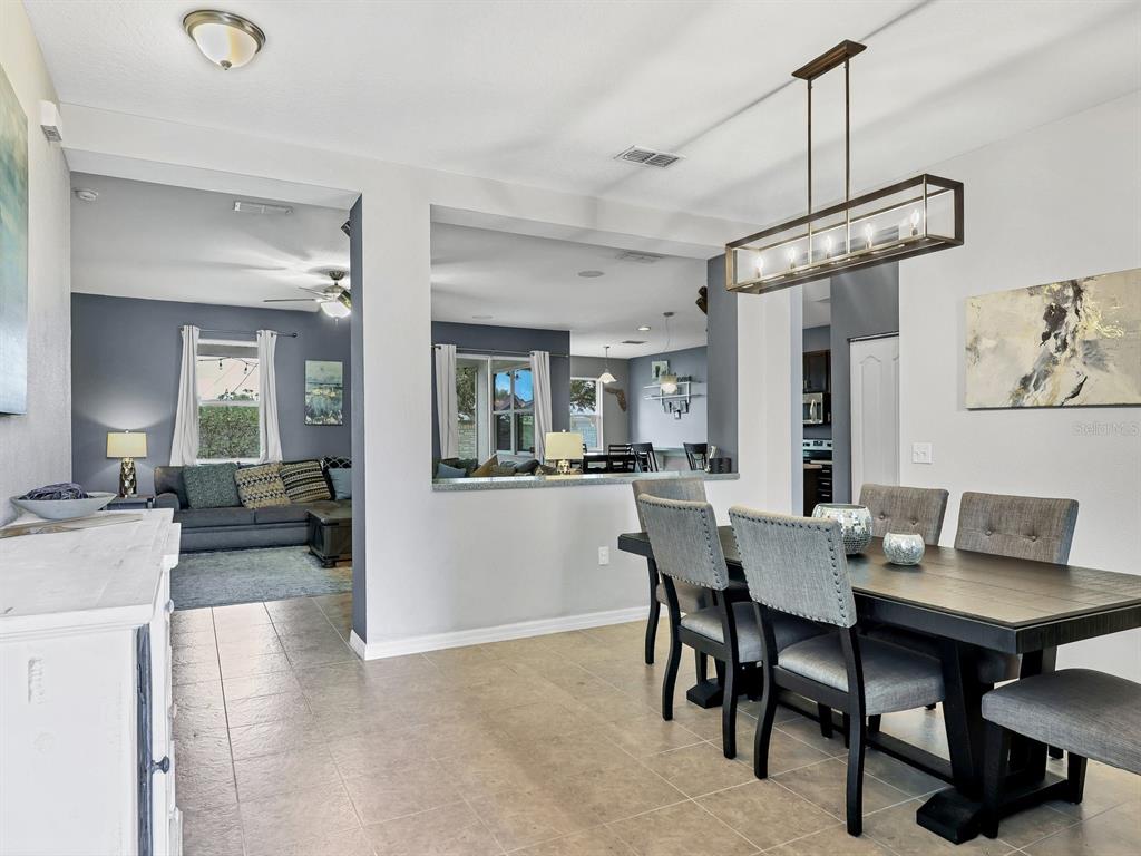 A dining area with a dark wood table and chairs opens into a living room — 6307 4TH STREET E, BRADENTON, FL