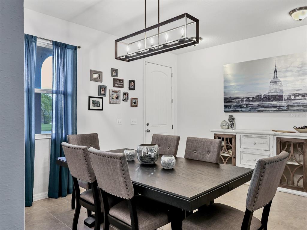 A dining room features a dark wood table, upholstered chairs, and a rectangular pendant light — 6307 4TH STREET E, BRADENTON, FL