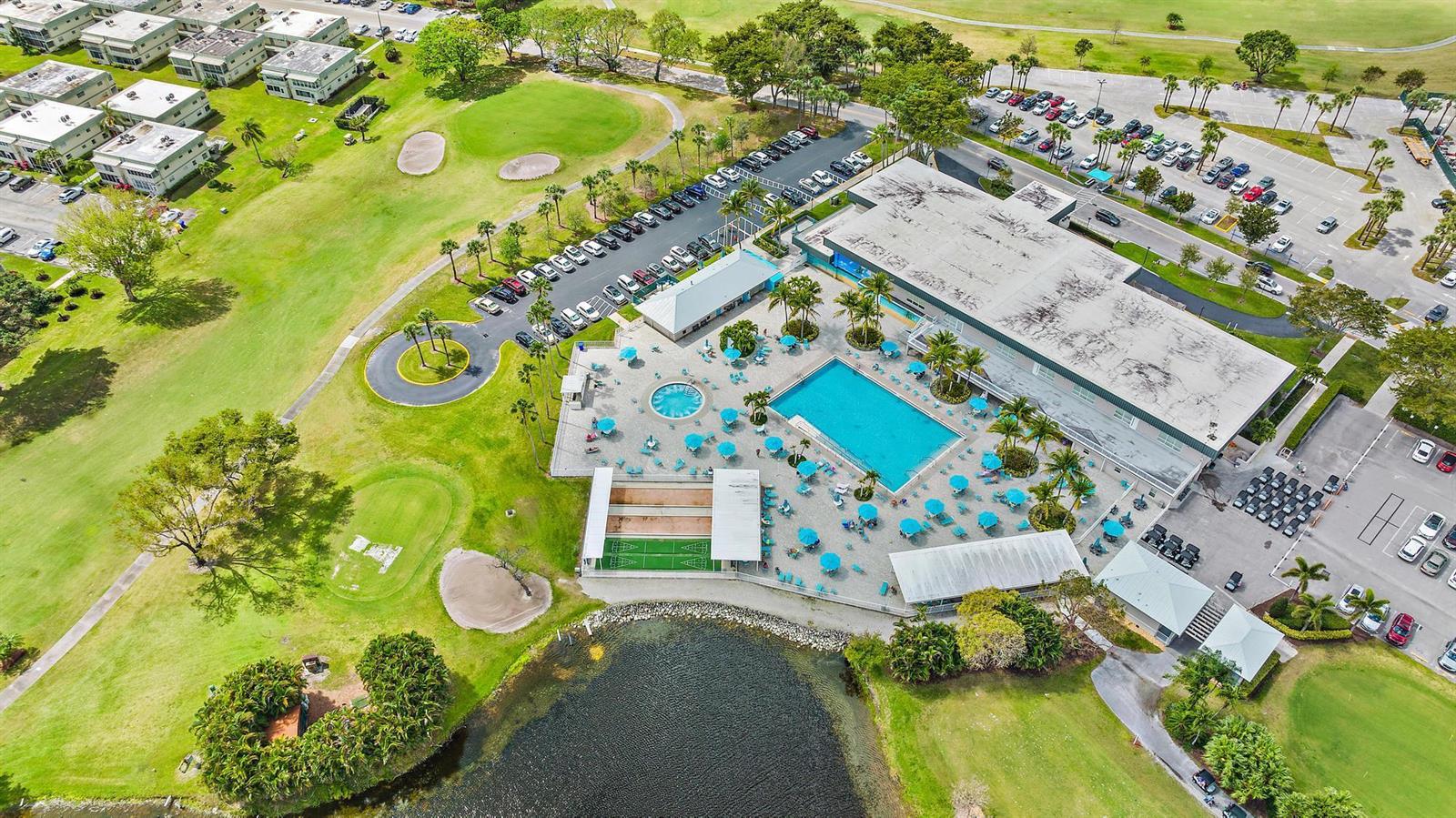 An aerial view shows a large swimming pool, clubhouse, parking lots, and surrounding golf course — 507 Capri K, Delray Beach FL 33484, DELRAY BEACH, FL