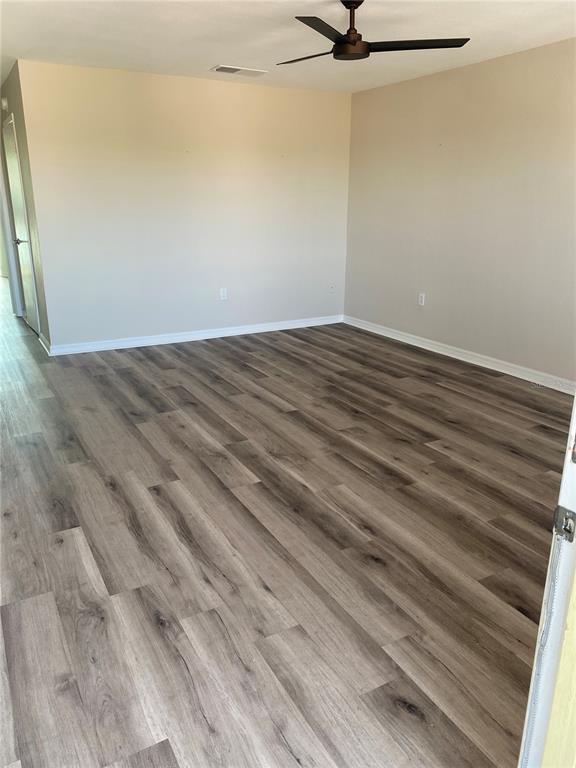 An empty room features light-colored walls, a ceiling fan, and wood-look vinyl plank flooring — 11100 86TH AVENUE UNIT 307, SEMINOLE, FL