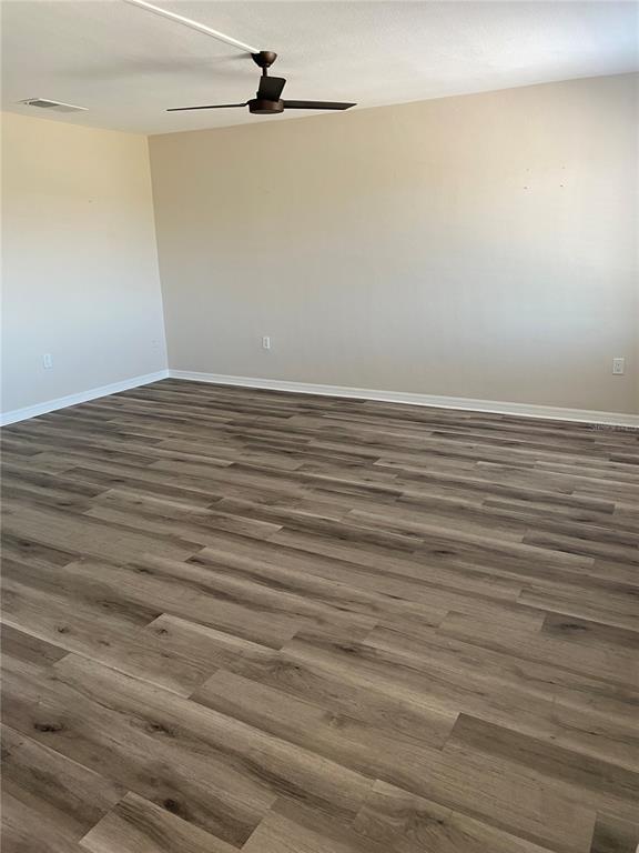 An empty room features light-colored walls, a ceiling fan, and wood-look plank flooring — 11100 86TH AVENUE UNIT 307, SEMINOLE, FL