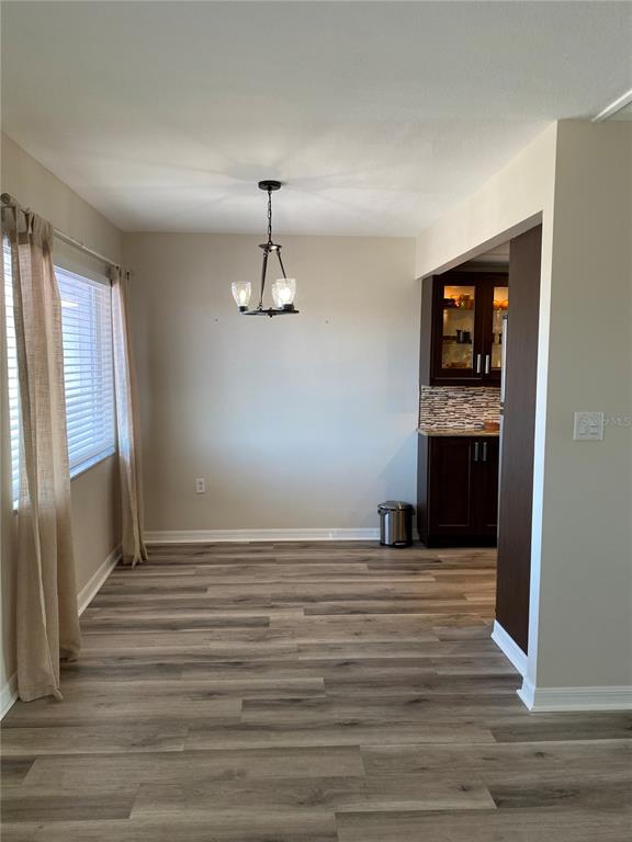 A dining area with wood-look flooring, a chandelier, and an adjacent kitchen with dark cabinetry — 11100 86TH AVENUE UNIT 307, SEMINOLE, FL