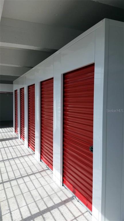 A row of storage units with red roll-up doors and white frames in a hallway — 602 BARBOSA AVE, SAN JUAN, PR