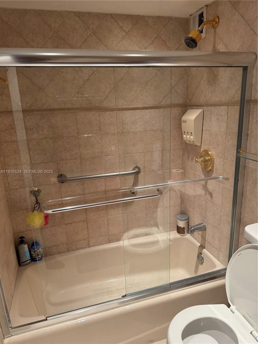 A screened-in balcony overlooks a residential neighborhood with a canal and trees — 800 NE 195th St # 714, Miami FL 33179, MIAMI, FL