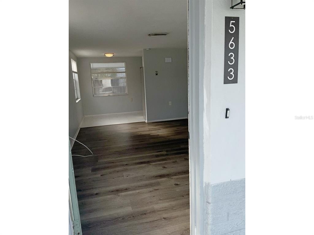 An exterior view looking through an open doorway into a room with wood-look flooring — 5633 GOLDEN NUGGET DRIVE, HOLIDAY, FL
