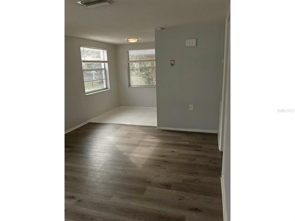 An interior view shows a living area with wood-look flooring and an adjacent tiled dining space — 5633 GOLDEN NUGGET DRIVE, HOLIDAY, FL