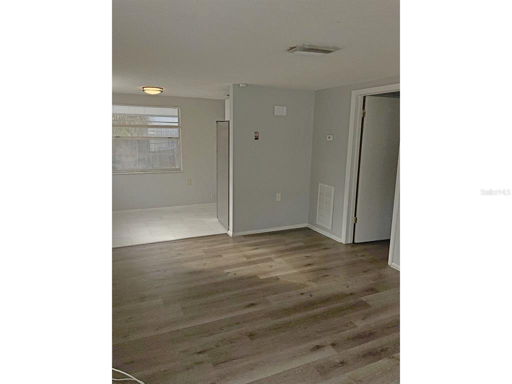 An interior view shows a living area with wood-look flooring leading to a tiled kitchen — 5633 GOLDEN NUGGET DRIVE, HOLIDAY, FL