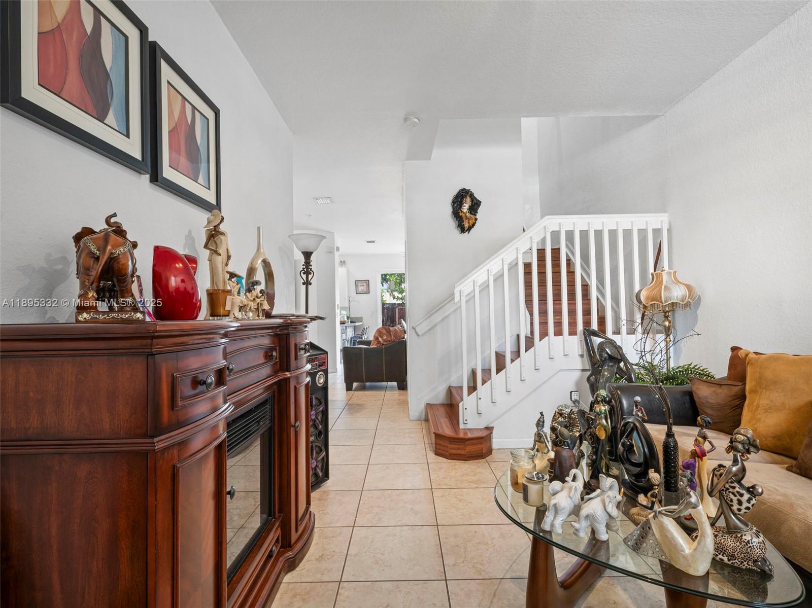 A living area features a wooden fireplace console, a staircase, and a glass coffee table — 2104 NE 3rd Ct, Homestead FL 33033, HOMESTEAD, FL