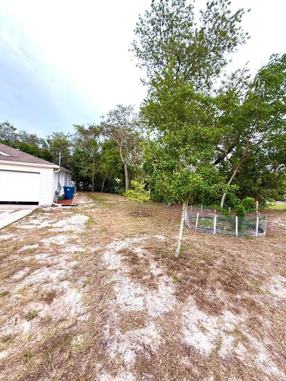 A side view of a house with a garage, a yard, and several trees — 1490 PIPER ROAD, SPRING HILL, FL