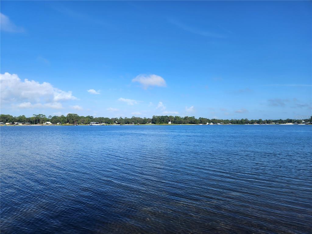 A wide view of a calm lake with a treeline along the distant shore — 22348 NE 112TH TERRACE, FORT MC COY, FL