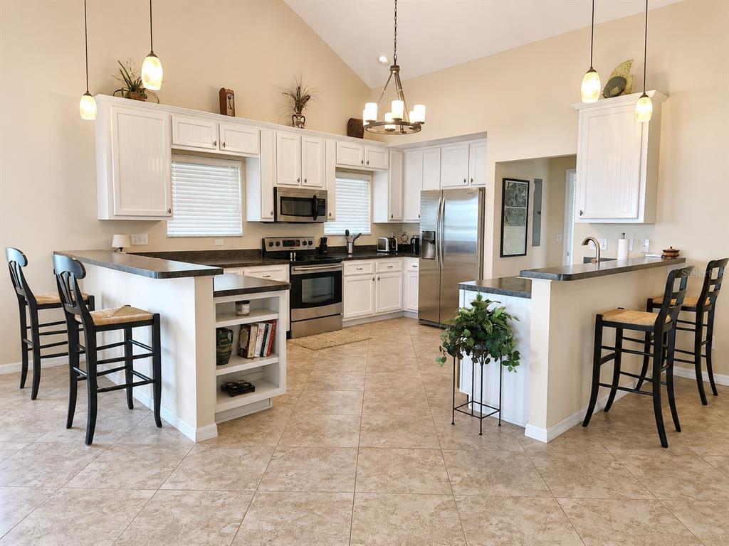 A kitchen with white cabinets, stainless steel appliances, a breakfast bar, and tile flooring — 22348 NE 112TH TERRACE, FORT MC COY, FL