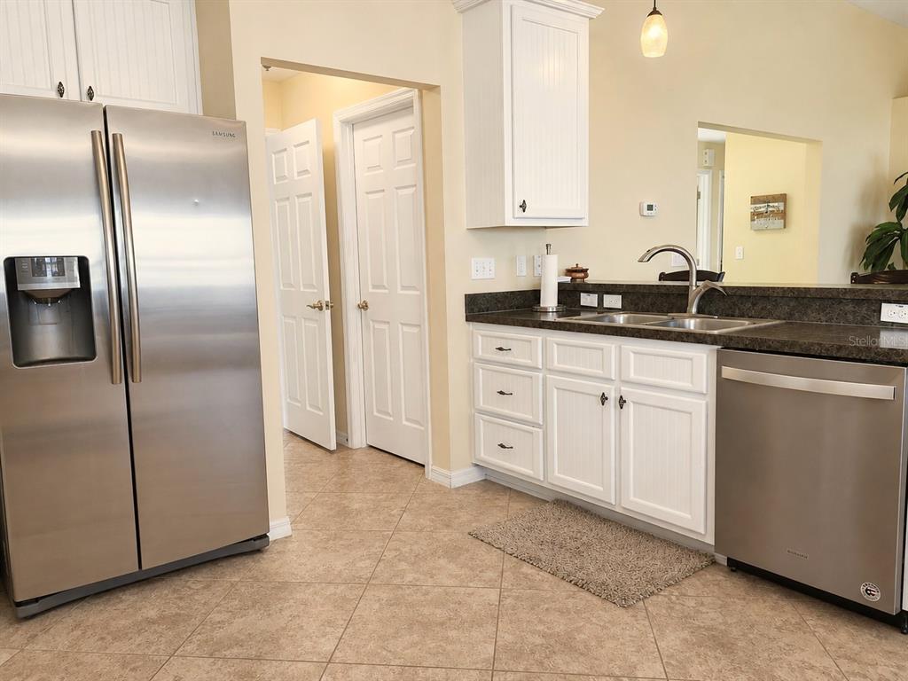 A kitchen features white cabinets, stainless steel appliances, a double sink, and beige tile flooring — 22348 NE 112TH TERRACE, FORT MC COY, FL