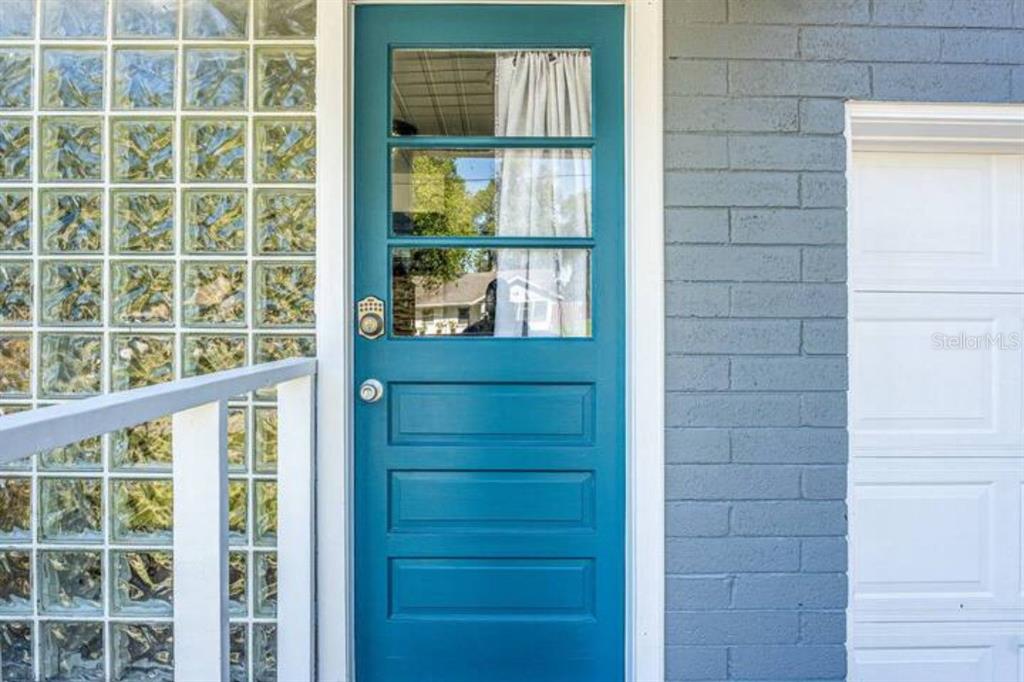 A teal door with glass panels sits beside a glass block wall and brick siding — 2014 NEWMAN ST UNIT 2, ORLANDO, FL