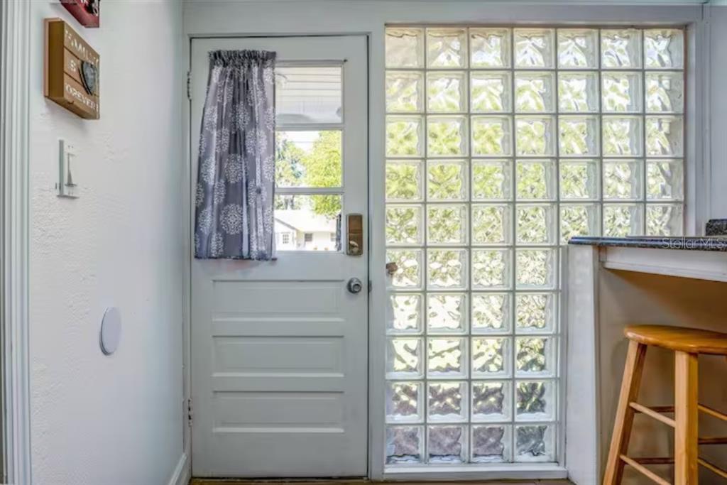 A white door with a patterned curtain sits next to a large glass block window — 2014 NEWMAN ST UNIT 2, ORLANDO, FL