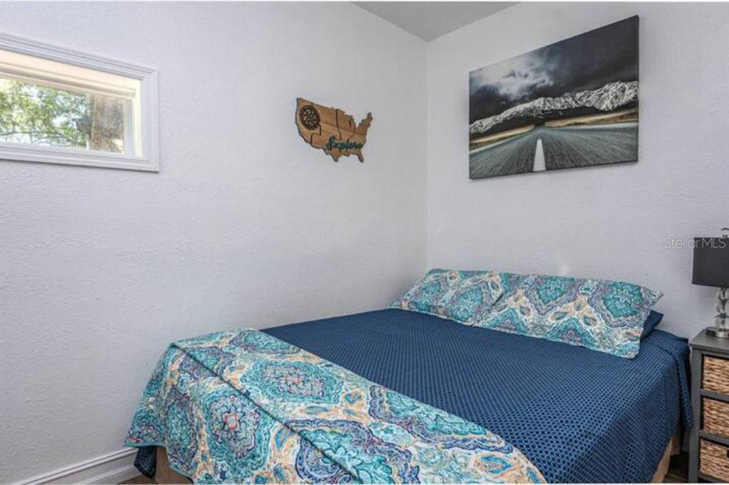A bedroom features a bed with a blue patterned quilt and a wall-mounted map decoration — 2014 NEWMAN ST UNIT 2, ORLANDO, FL