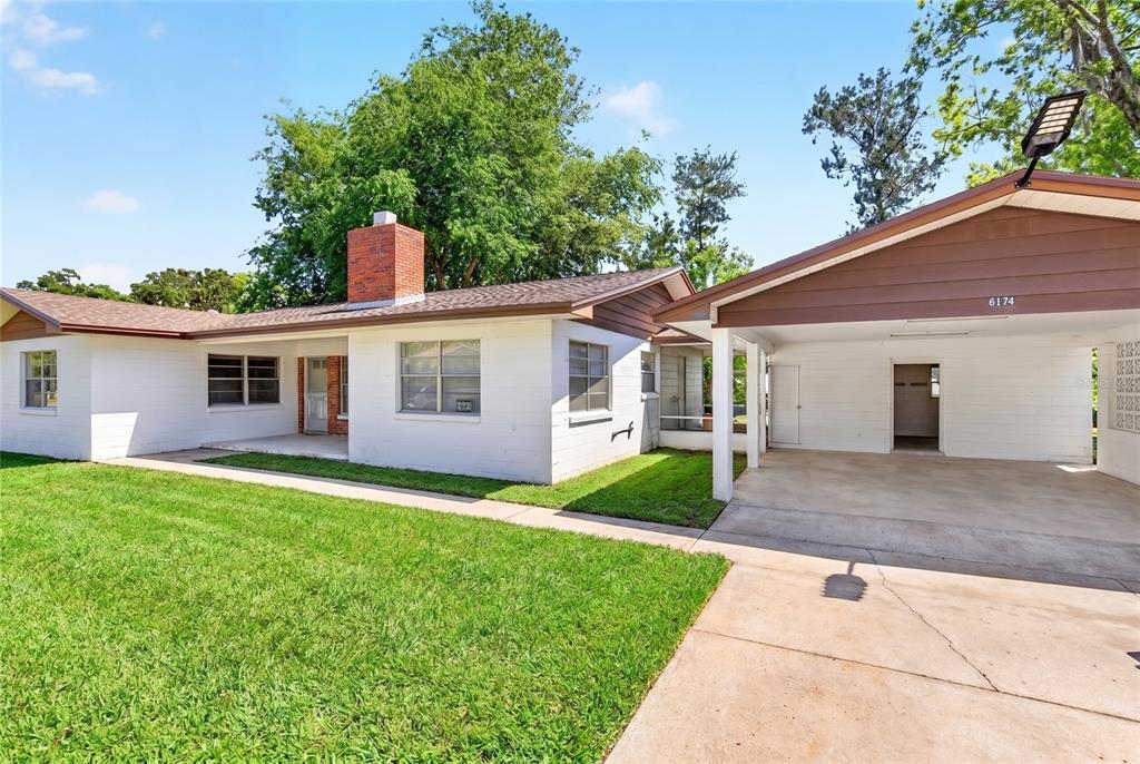A white brick house with a brown roof, a chimney, and an attached carport — 6174 SE 125TH PLACE, BELLEVIEW, FL