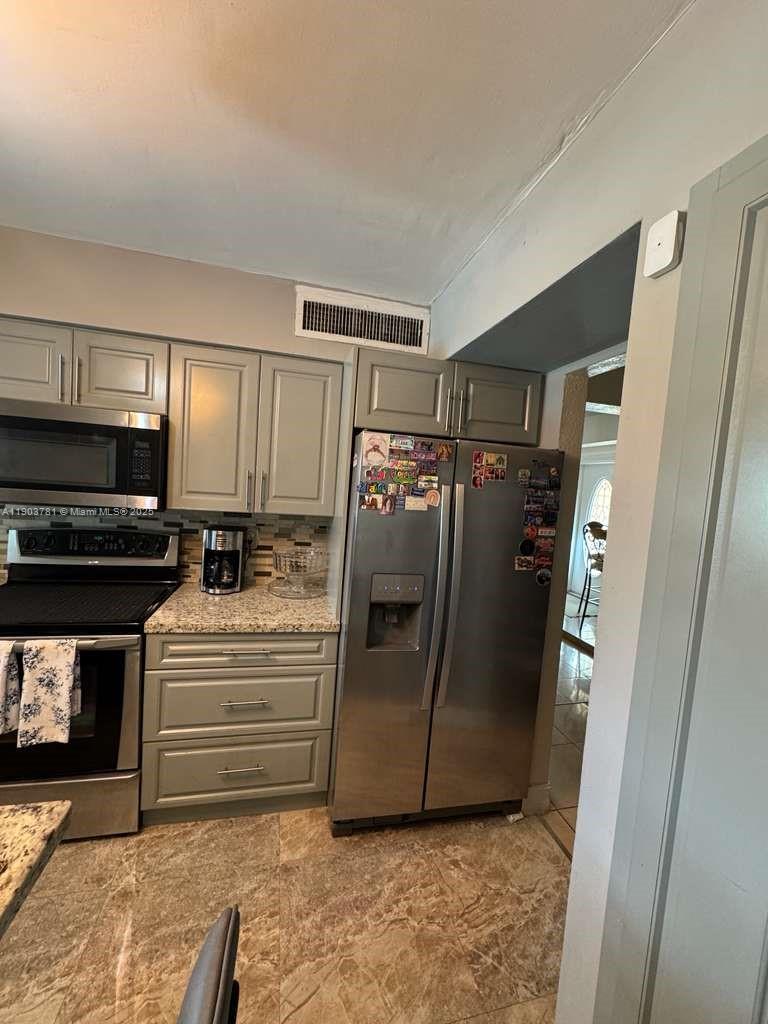 A kitchen features grey cabinets, stainless steel appliances, granite countertops, and tiled flooring — 6391 SW 34th St, Miramar FL 33023, MIRAMAR, FL