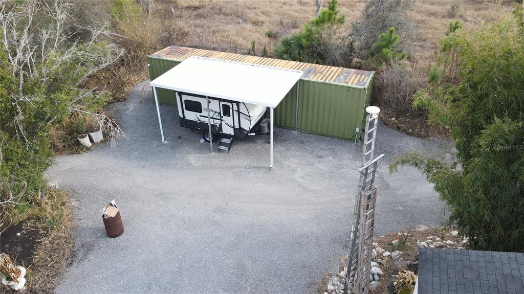 An aerial view shows a travel trailer parked under a carport next to a shipping container — 345 N HACIENDA STREET, CLEWISTON, FL