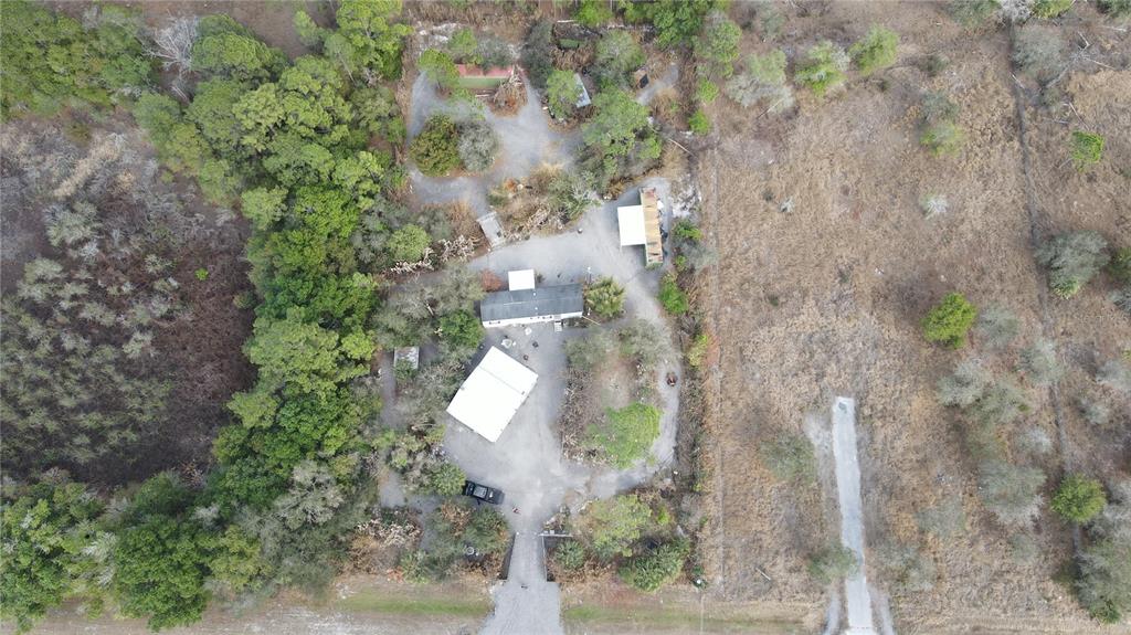 An aerial view shows a rural property with a house, outbuildings, and surrounding wooded land — 345 N HACIENDA STREET, CLEWISTON, FL