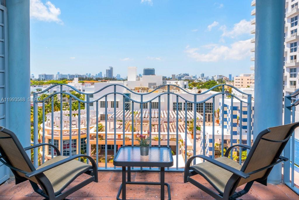 A balcony with two chairs and a small table overlooks a city skyline — 1500 Ocean Drive # 609, Miami Beach FL 33139, MIAMI BEACH, FL