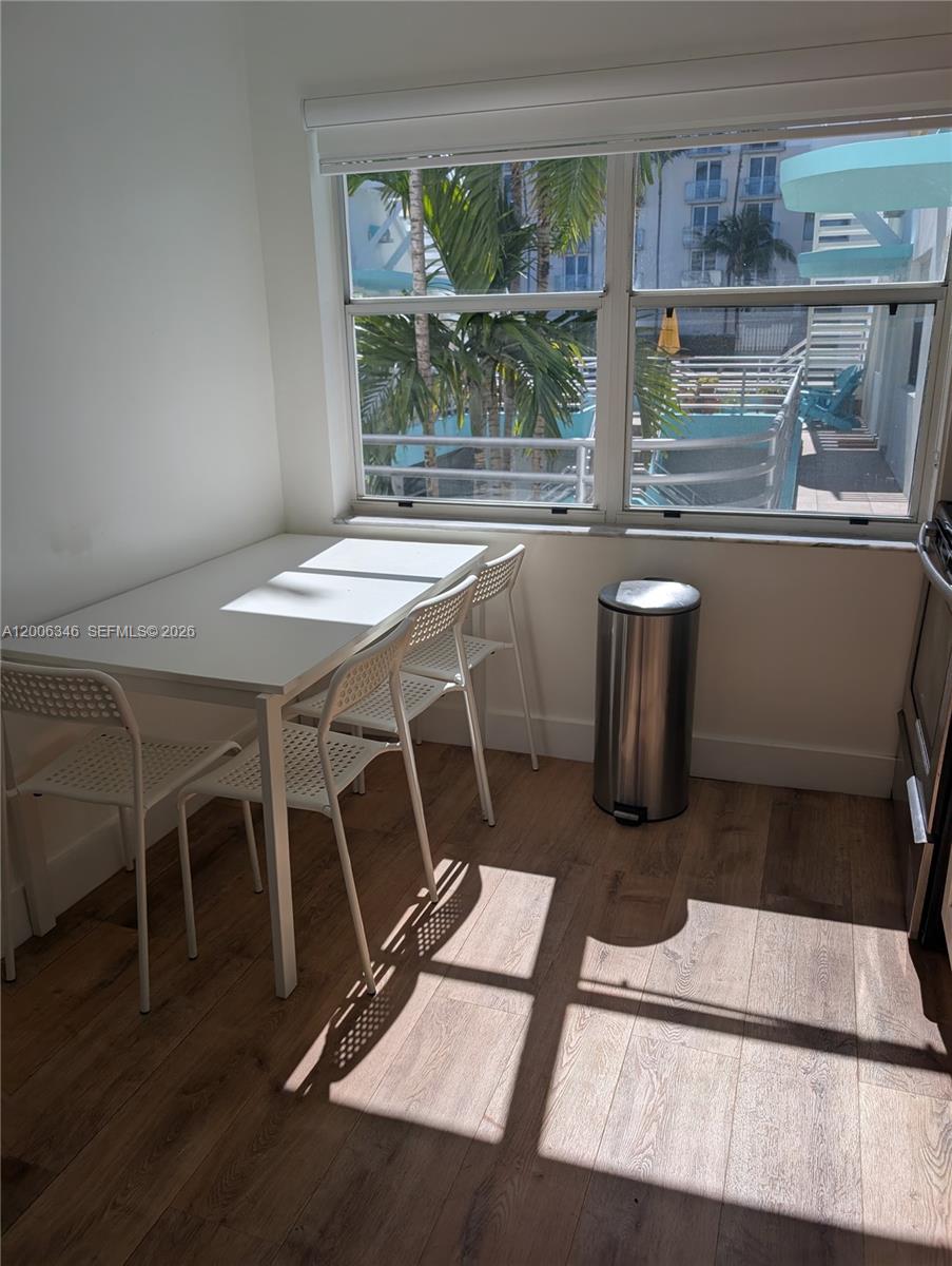 A dining area features a white table, three chairs, a trash can, and a window — 326 Wilson St # 201, Hollywood FL 33019, HOLLYWOOD, FL