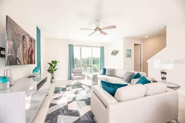 A bright living room features a white sectional sofa, a geometric rug, and a ceiling fan — 792 DRIVING RANGE COURT, REUNION, FL