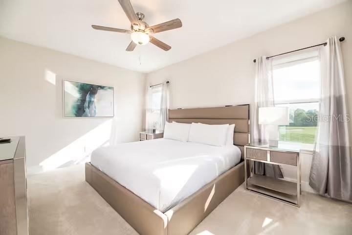 A bedroom features a platform bed, a ceiling fan, and a window with curtains — 792 DRIVING RANGE COURT, REUNION, FL
