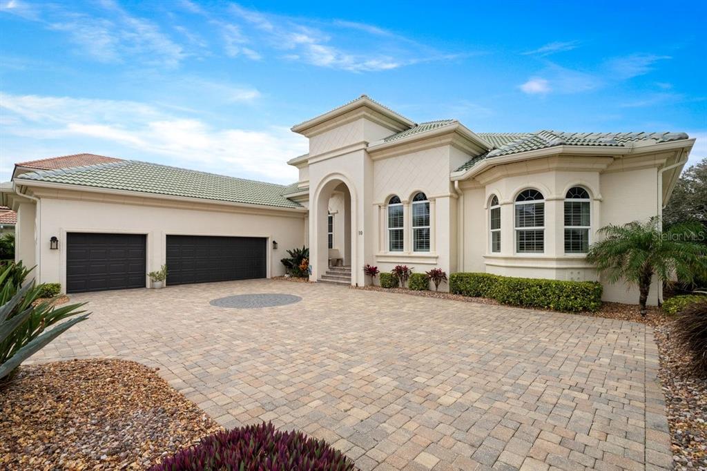 A beige house with a three-car garage and a paved driveway under a blue sky — 10 RUE GRANDE MER, PALM COAST, FL