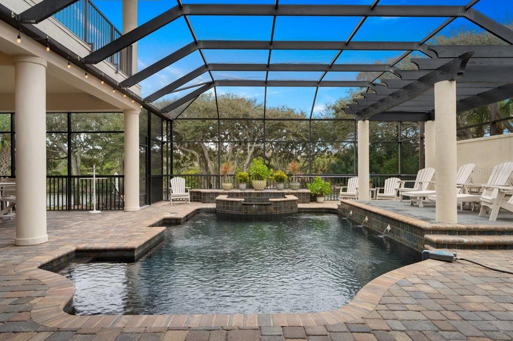 A screened-in patio features a swimming pool with a raised spa and stone pavers — 10 RUE GRANDE MER, PALM COAST, FL