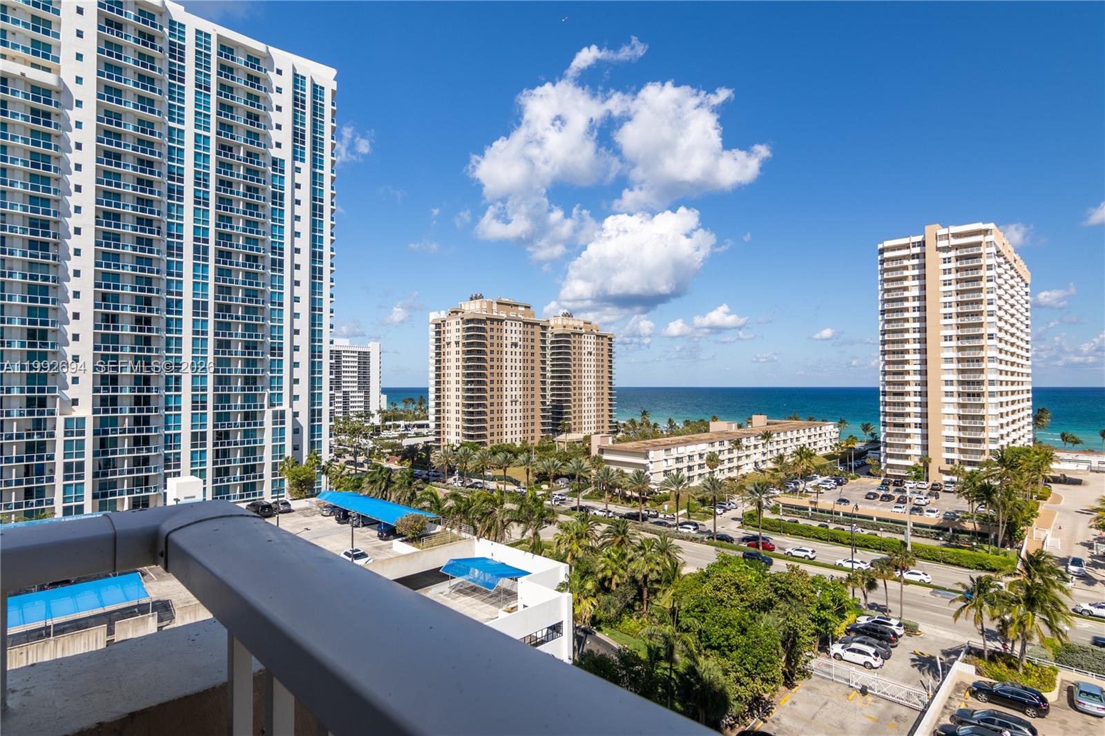 A high-angle view shows a balcony railing overlooking a coastal city with high-rise buildings — 1965 S Ocean Dr # 9F, Hallandale Beach FL 33009, HALLANDALE BEACH, FL